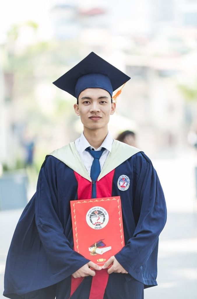 Proud graduate in academic gown holding diploma, celebrating academic success.