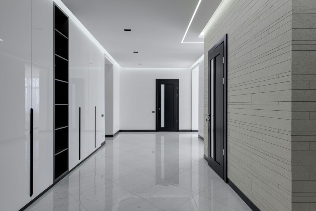 pexels-photo-6238610-6238610 Wide corridor in modern house with white tiled walls and floor black wooden doors and shelves for storage built in wall